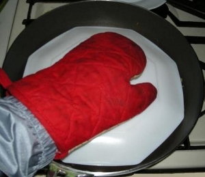 フライパンに皿をかぶせ手袋をした手を添えてひっくり返し皿に盛る